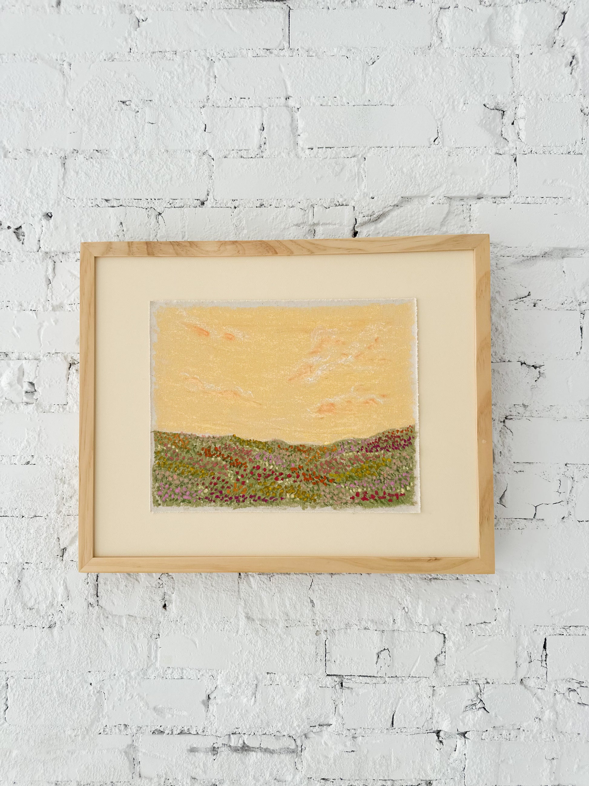 Framed landscape artwork on a brick white wall