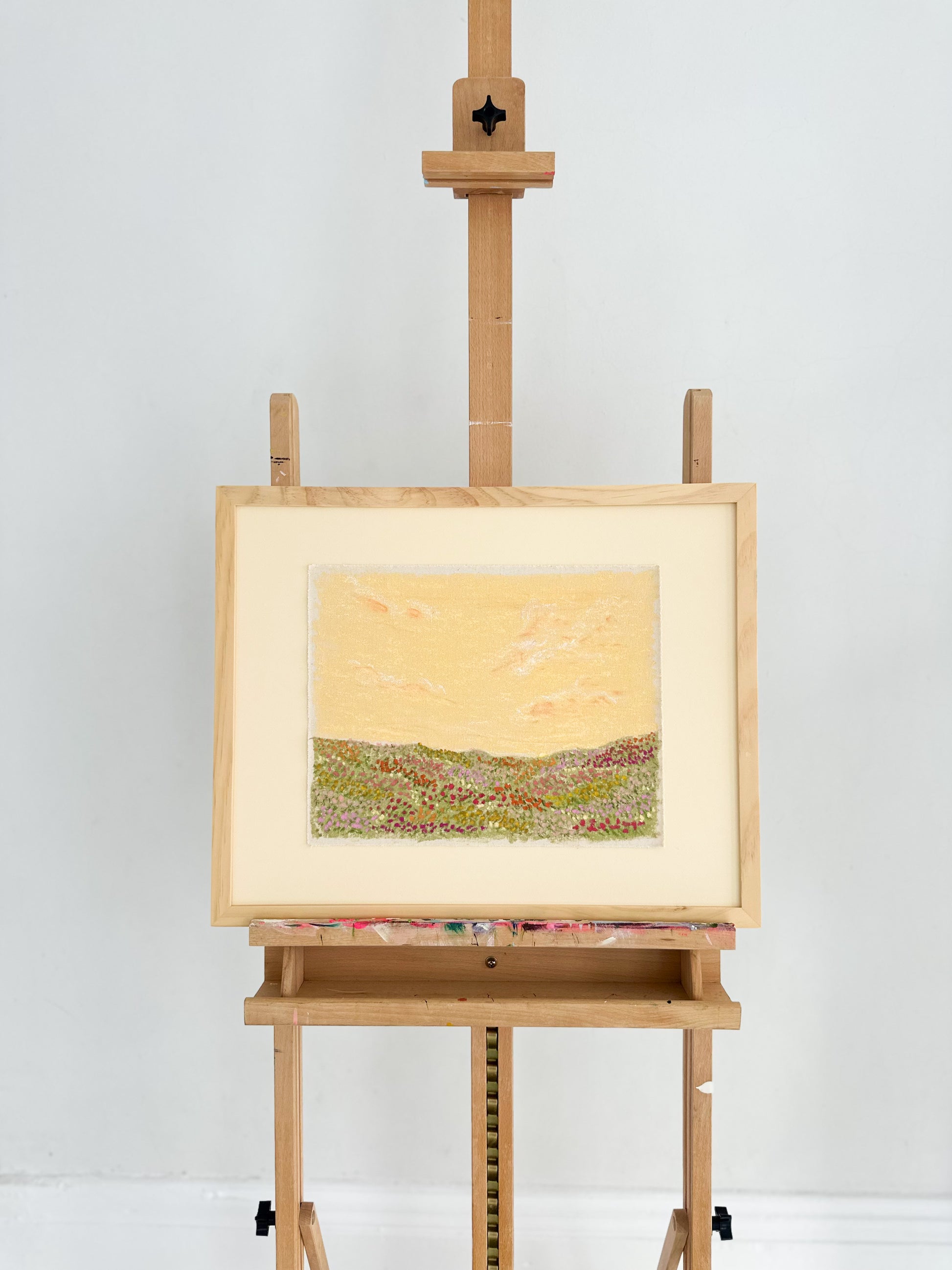 Landscape painting on a wooden easel against a white background