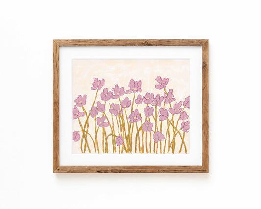 An art print of pink flowers on a cream background framed in a natural wood frame and displayed against a white backdrop.