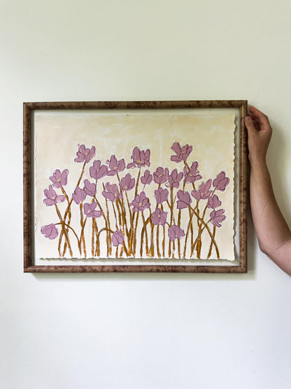 Framed artwork with pink floral design on a white wall