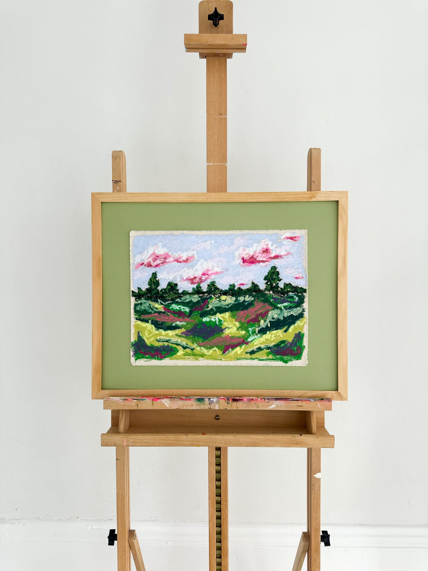 Painting of a landscape on a wooden easel against a white background