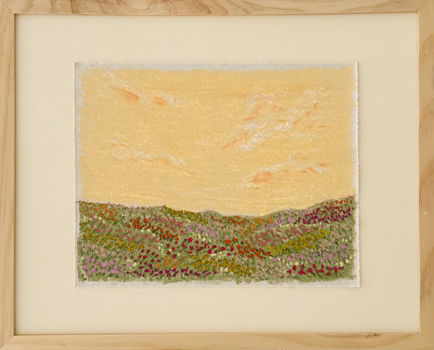 Framed artwork of a landscape with a yellow sky and green flower field.