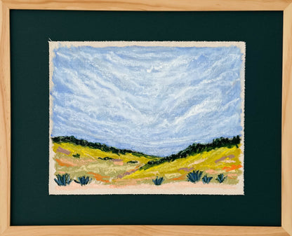 Framed artwork of a landscape with a blue sky and green fields.