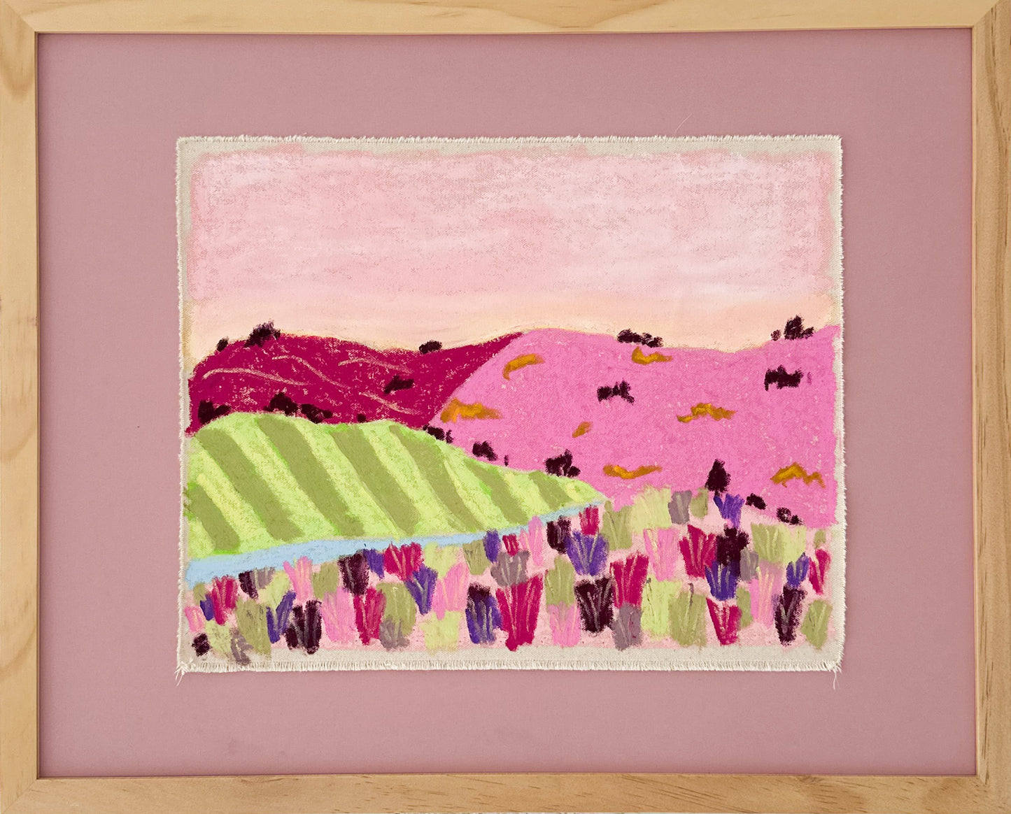 A framed, colorful landscape painting depicting rolling hills in pinks and greens.