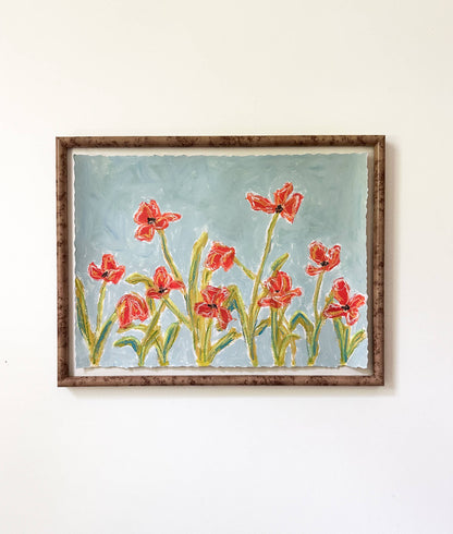 a framed painting of orange flowers with green stems painted on a dusty blue background and hung on a white wall.