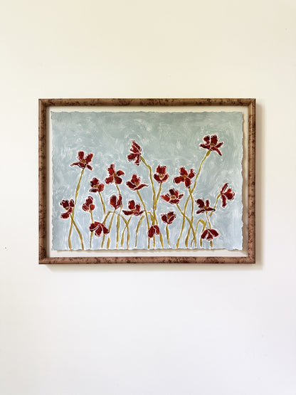deep blue flowers painted on a dusty blue background framed and hung on a white wall
